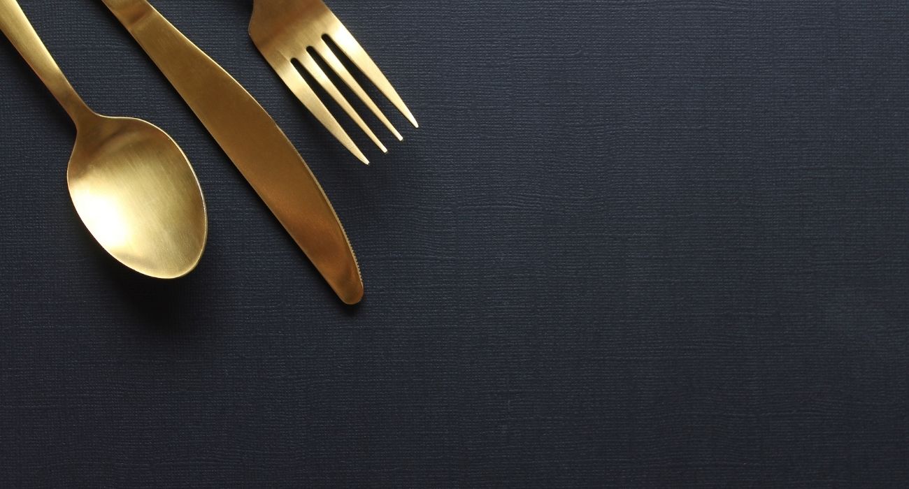 gold spoon,fork, and knife on black backdrop
